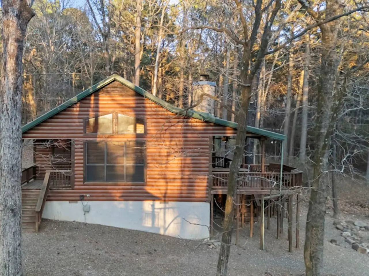 Cozy log cabin nestled among towering trees with plenty of deck space and natural light.