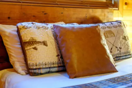 Cozy log cabin bedroom with plush pillows and natural wood beams creating that perfect mountain retreat vibe.
