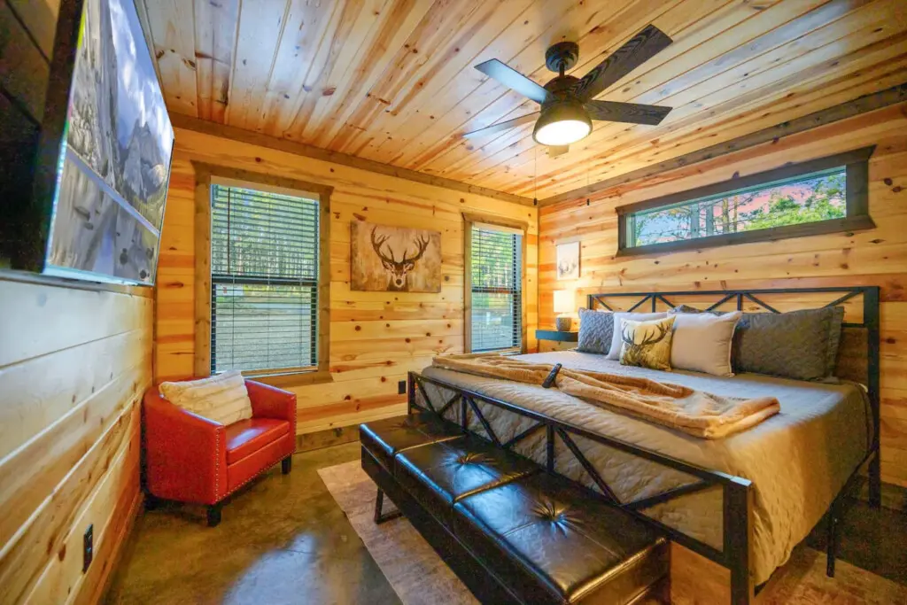 This cozy log cabin bedroom feels like the perfect hideaway with those warm wood walls, a super comfy bed loaded with pillows, and windows that basically bring the forest right inside.