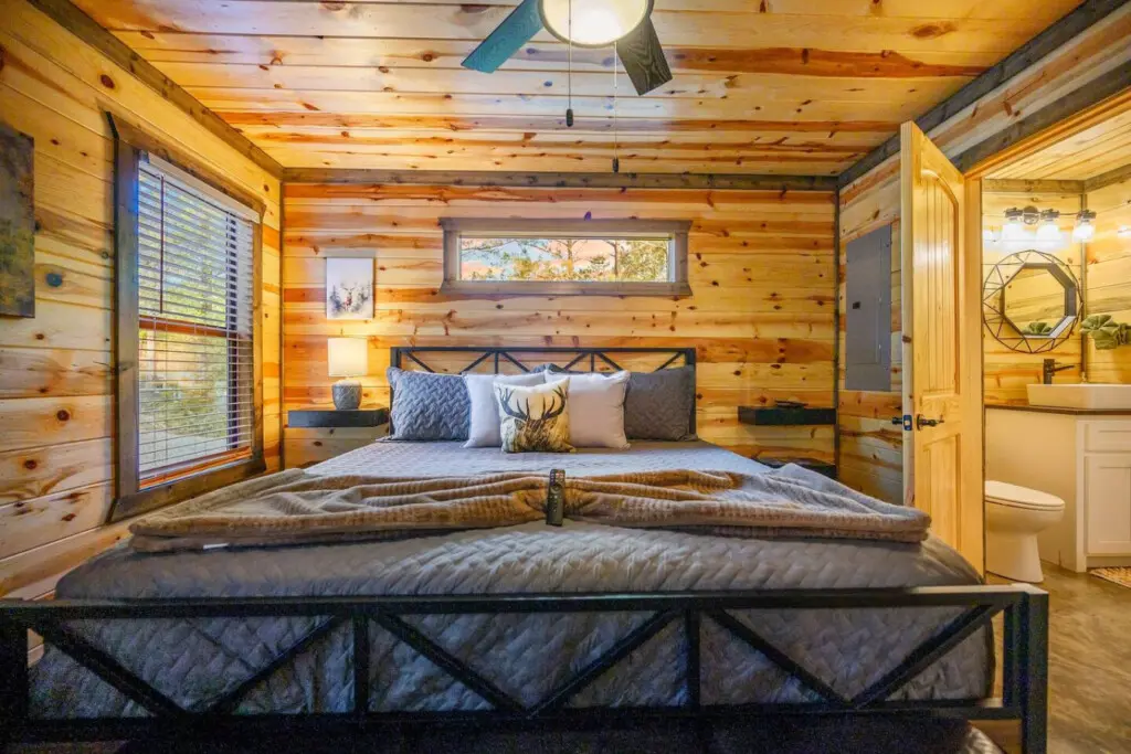 This cozy log cabin bedroom has serious retreat vibes with those wooden walls wrapping around you, a couple of beds to choose from, and windows perfectly framing the forest outside.