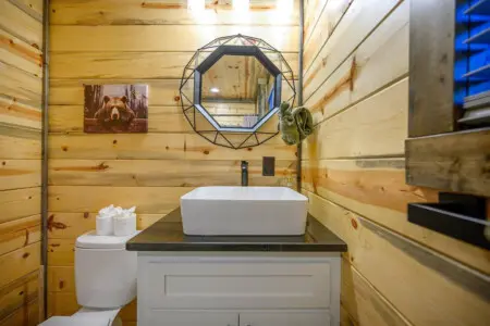 This bathroom hits the perfect balance between rustic cabin charm and modern updates, with those warm wood walls framing a sleek white vessel sink that honestly looks like something you'd see in a fancy spa.