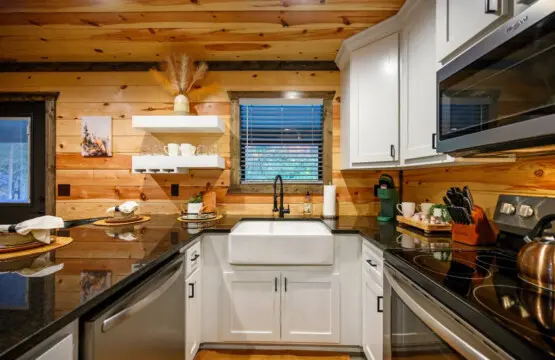 This kitchen is the perfect blend of rustic charm and modern convenience, with those crisp white cabinets and sleek black countertops looking right at home against all that warm knotty pine.