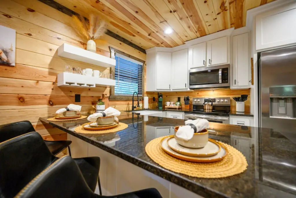 This kitchen is basically made for cooking and hanging out together—with that massive island, warm wood everywhere, and those white cabinets that keep things feeling fresh and modern.