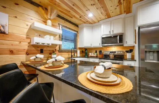 This kitchen is basically made for cooking and hanging out together—with that massive island, warm wood everywhere, and those white cabinets that keep things feeling fresh and modern.