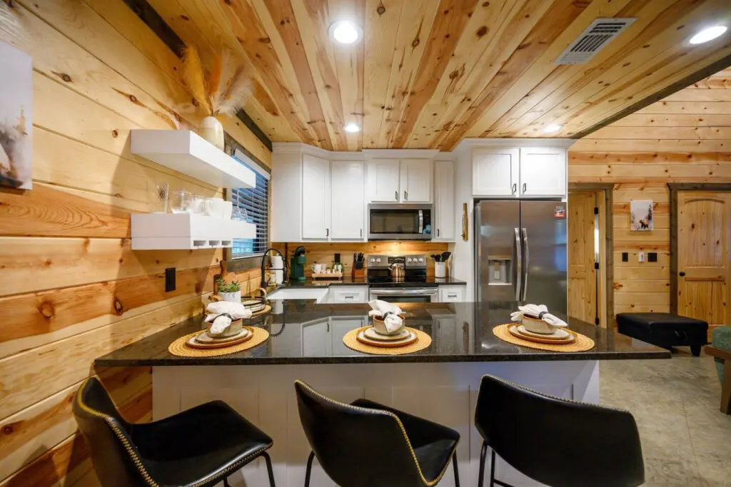 This gorgeous kitchen is basically built for gathering—soaring wood ceilings, that huge island with seating for days, and stainless steel appliances that actually look good against all the warm wood surrounding you.