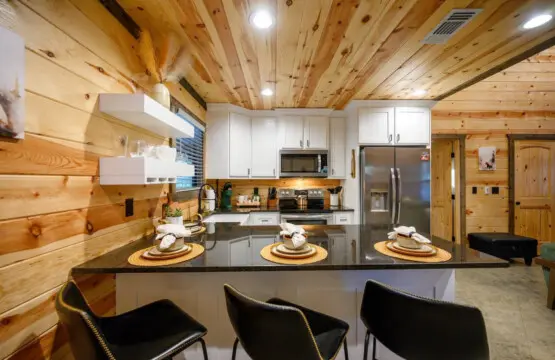 This gorgeous kitchen is basically built for gathering—soaring wood ceilings, that huge island with seating for days, and stainless steel appliances that actually look good against all the warm wood surrounding you.