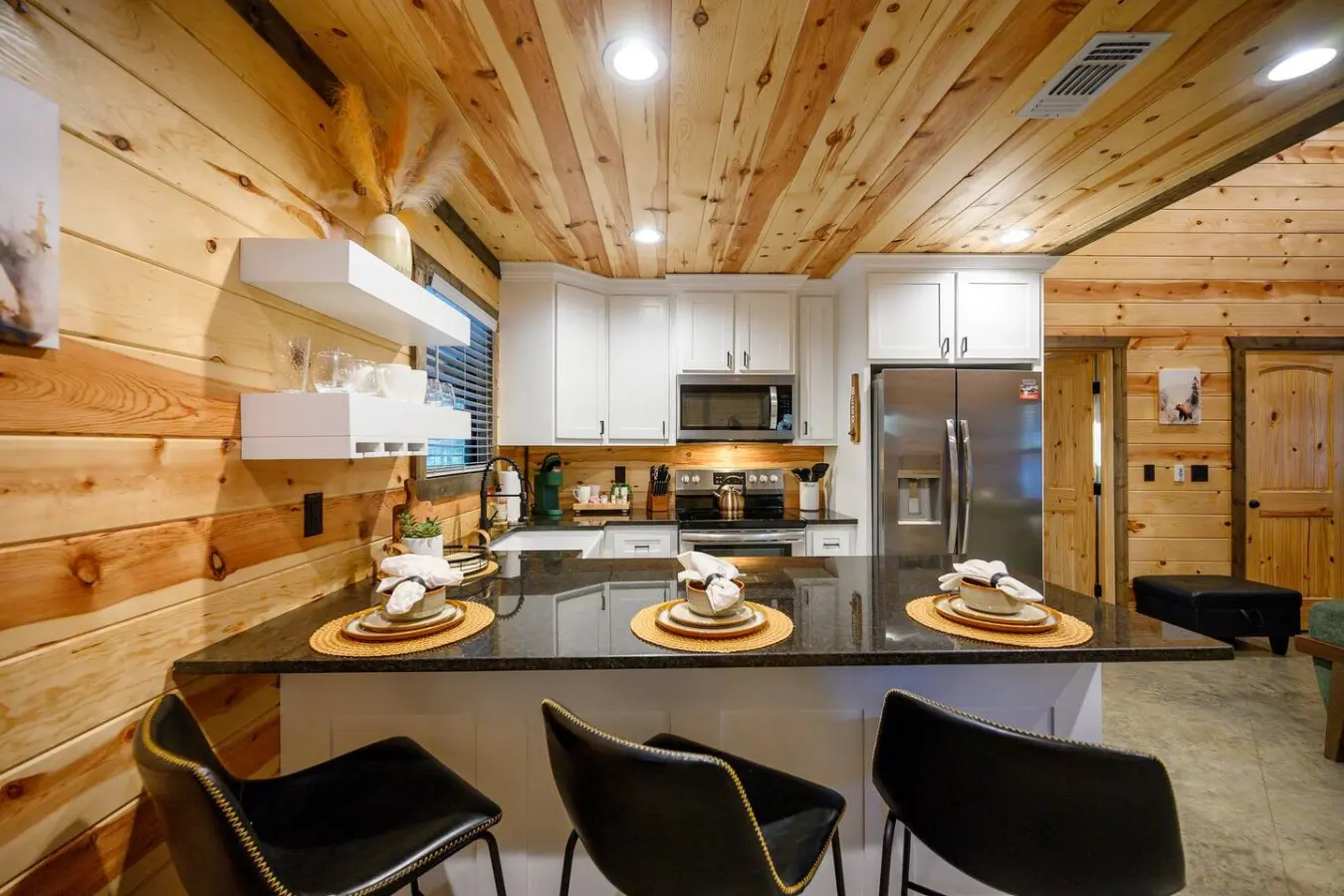 This gorgeous kitchen is basically built for gathering—soaring wood ceilings, that huge island with seating for days, and stainless steel appliances that actually look good against all the warm wood surrounding you.