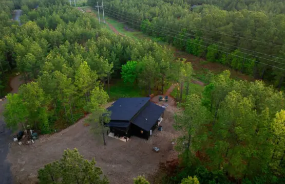 This modern black cabin sits perfectly nestled in the forest with nothing but tall pines surrounding you, a river winding through the trees, and those power lines being the only real reminder that civilization exists.