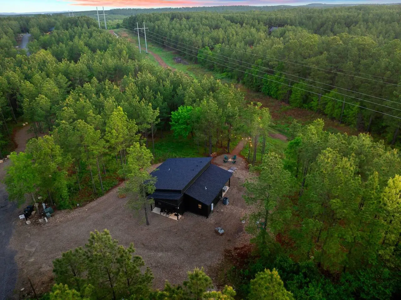 This modern black cabin sits perfectly nestled in the forest with nothing but tall pines surrounding you, a river winding through the trees, and those power lines being the only real reminder that civilization exists.