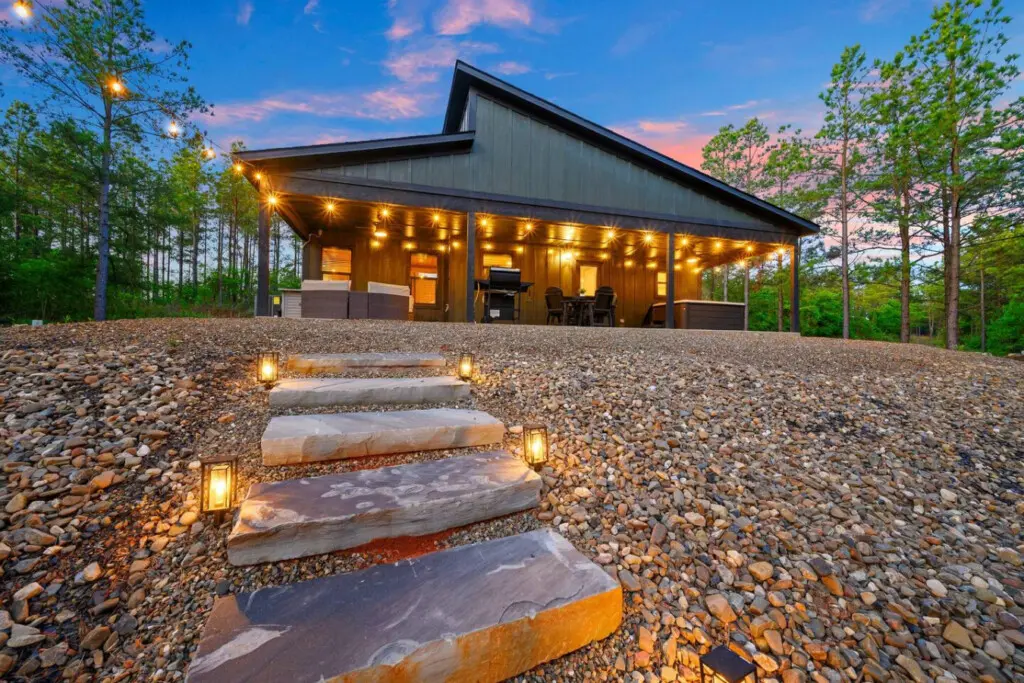 The illuminated stepping stones guide you right up to this sleek modern cabin, making those twilight arrivals feel like walking into your own private forest sanctuary.