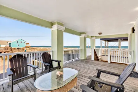 Imagine spending your entire beach vacation on this sprawling covered deck—multiple lounge spots, unobstructed ocean views, and that perfect coastal breeze that makes you never want to go inside.