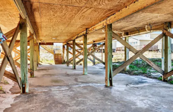 Beneath the soaring ceilings and weathered beams, this sheltered under-home space is your private transition zone between cozy indoors and endless sandy shores—complete with direct beach access and that perfect coastal breeze flowing through.
