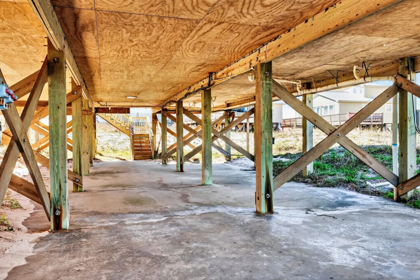 Beneath the soaring ceilings and weathered beams, this sheltered under-home space is your private transition zone between cozy indoors and endless sandy shores—complete with direct beach access and that perfect coastal breeze flowing through.