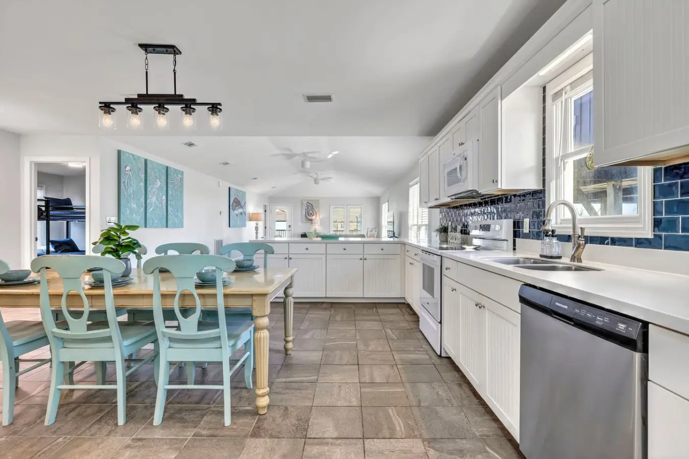 This bright, inviting kitchen and dining area is basically where the whole crew will want to hang out—plenty of space to cook together, gather around that beautiful wood table, and soak in all the light and coastal charm that makes every meal feel like pa