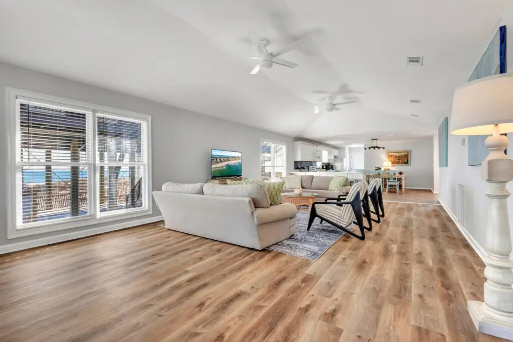 This open-concept beachfront home is basically built for lounging—huge windows frame those ocean views, multiple ceiling fans keep the breeze flowing, and you've got plenty of space to spread out and actually relax.