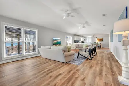 This open-concept beachfront home is basically built for lounging—huge windows frame those ocean views, multiple ceiling fans keep the breeze flowing, and you've got plenty of space to spread out and actually relax.