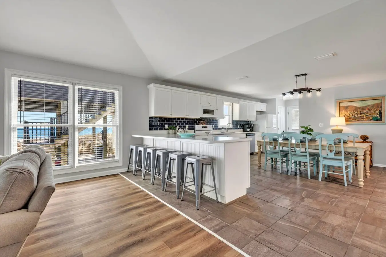 This open-concept living space is basically built for the ultimate beach getaway—huge windows framing those ocean views, a chef's kitchen for cooking together, and a casual dining area where everyone gathers naturally throughout the day.