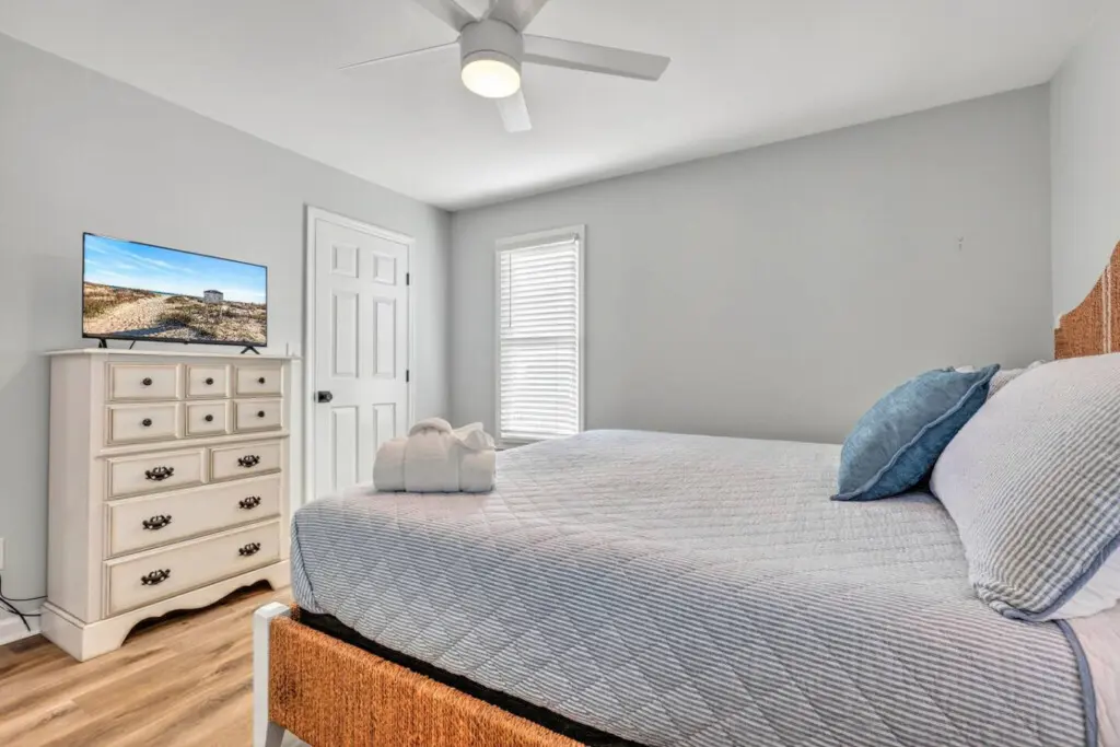 Wake up in this calm, light-filled bedroom with everything you need for a perfect night's sleep—soft bedding, a gently spinning ceiling fan, and that peaceful coastal quiet that makes you never want to leave.