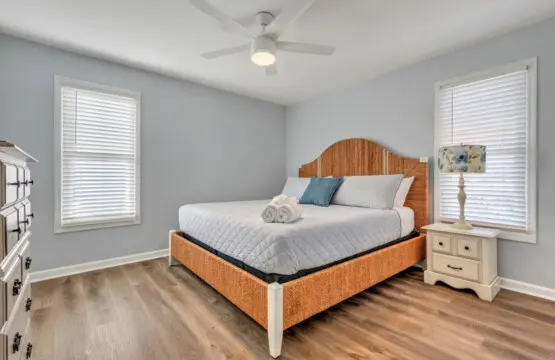 Wake up in this serene coastal bedroom where soft natural light filters through the shutters and a ceiling fan keeps the ocean breeze flowing all night long.