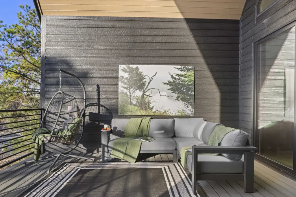 Unwind on this serene covered deck with hanging chairs, modern seating, and panoramic forest views.