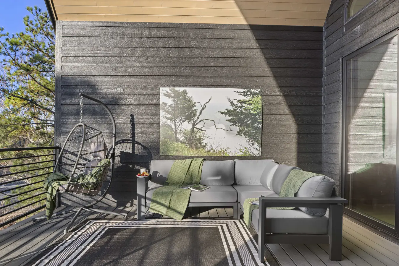 Unwind on this serene covered deck with hanging chairs, modern seating, and panoramic forest views.