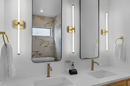 Double vanity with brushed gold fixtures and those sleek vertical sconces means no one's fighting over mirror space.
