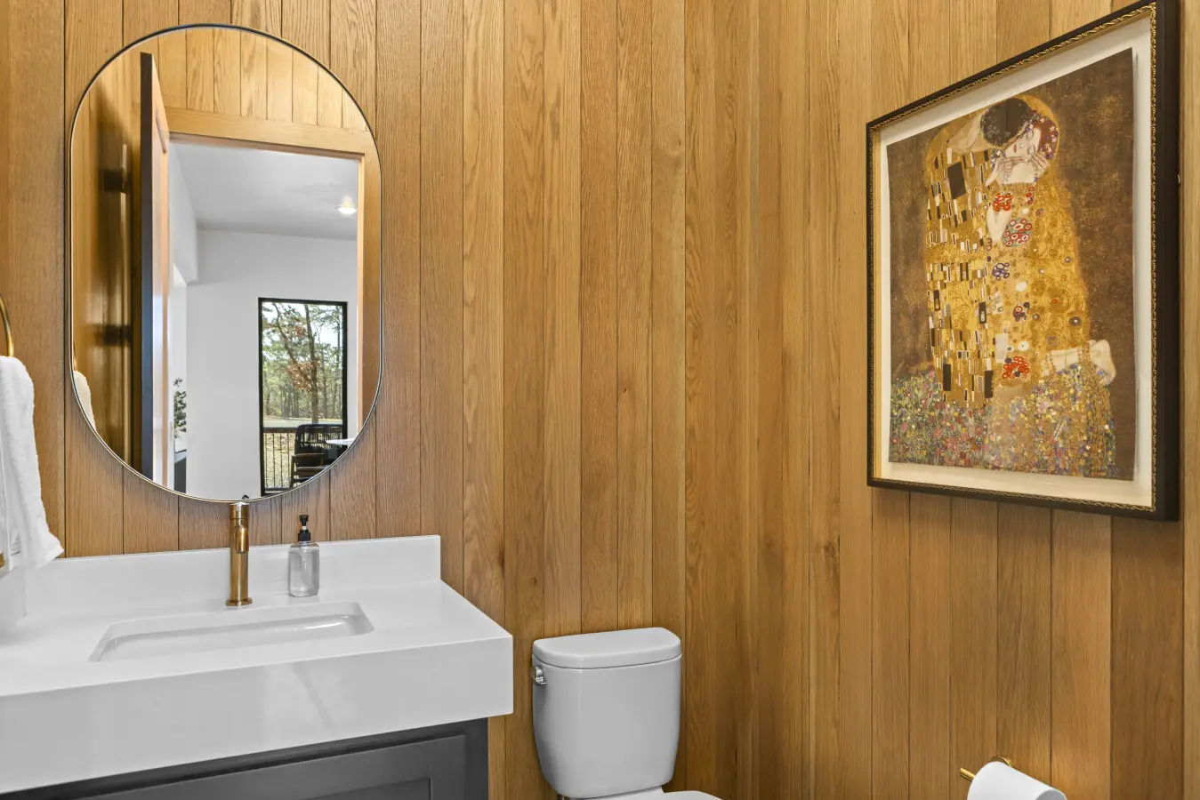 Even the powder room gets the spa treatment with warm wood paneling and a framed Klimt print.