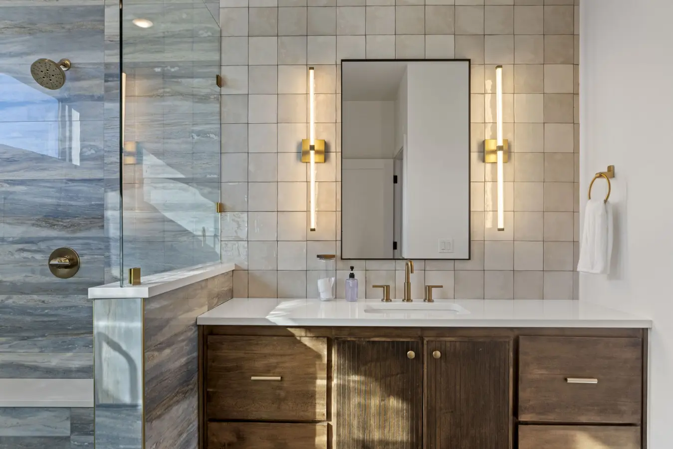 The brushed gold fixtures and those sleek sconces give this bathroom a boutique hotel feel.
