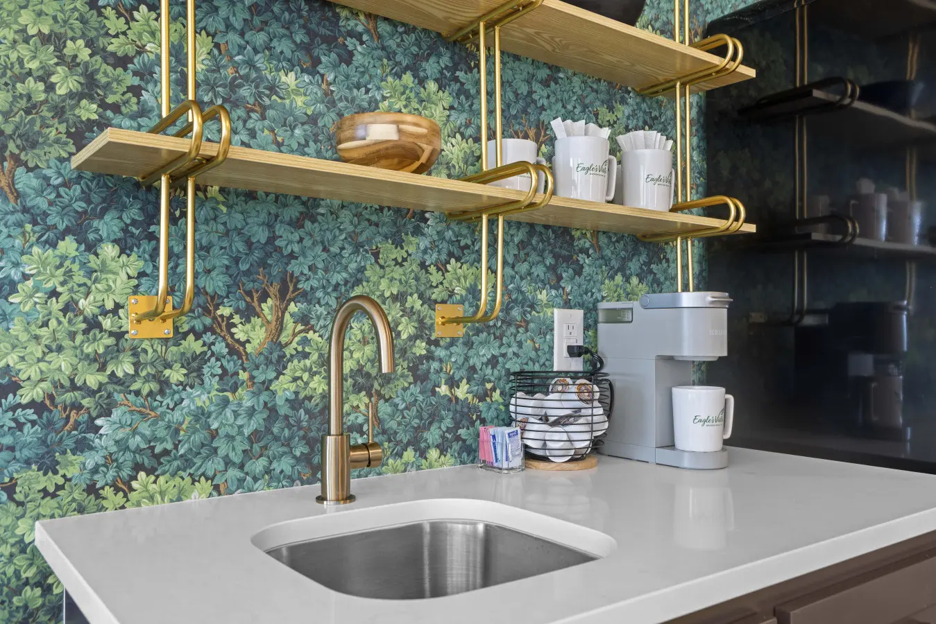 The wet bar's got a Keurig, custom Eagle's Vista mugs, and that botanical wallpaper is a whole vibe.