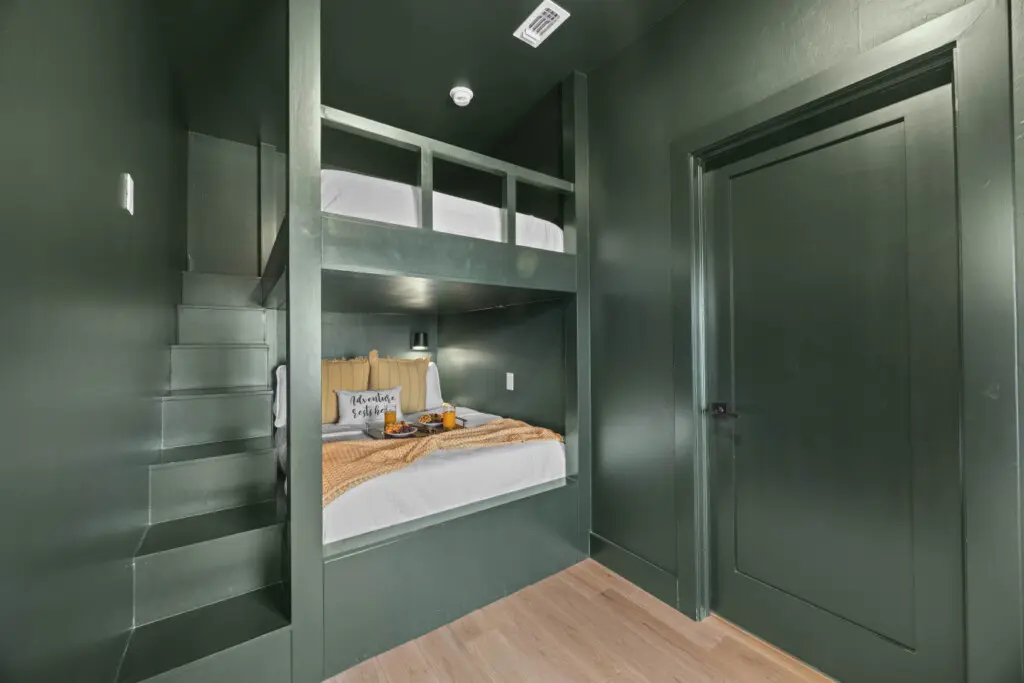 The kids (or let's be honest, adults) get this moody green bunk setup with built-in stairs and cozy reading lights.