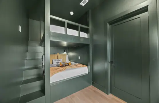 The kids (or let's be honest, adults) get this moody green bunk setup with built-in stairs and cozy reading lights.