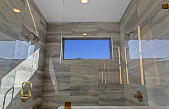The dual-head shower in this marble-tiled bathroom feels pretty spa-like, with that window framing nothing but blue sky.