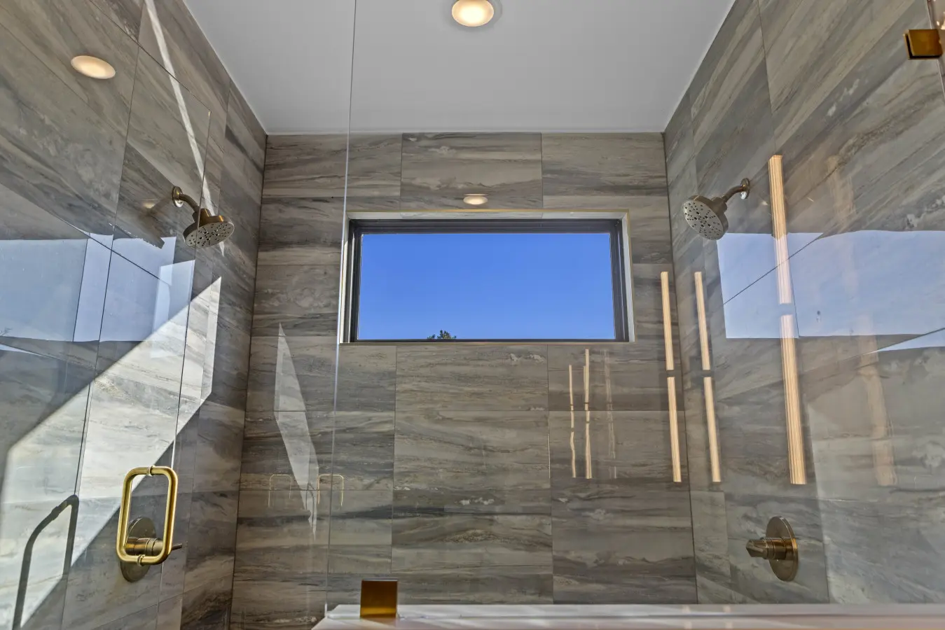 The dual-head shower in this marble-tiled bathroom feels pretty spa-like, with that window framing nothing but blue sky.