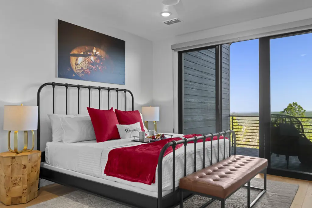 One of the king bedrooms has a black iron bed, red velvet accents, and a private balcony overlooking the hills.