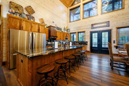 This gorgeous log cabin kitchen features soaring ceilings, stainless steel appliances, and a massive island perfect for gathering.