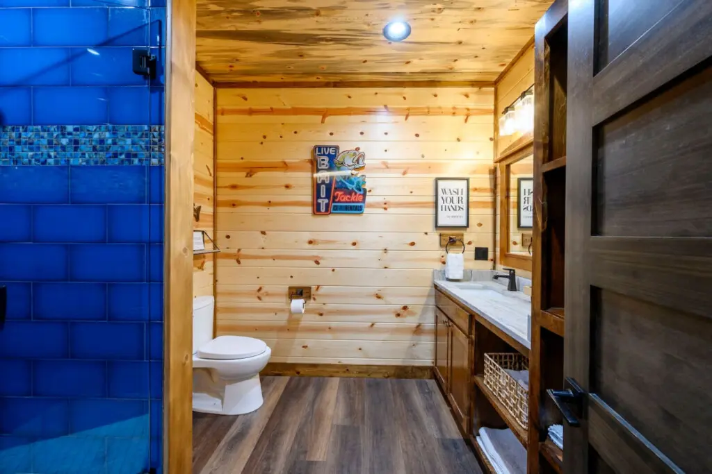 This bathroom features a fun fishing cabin vibe with knotty pine walls, modern fixtures, and a luxe walk-in shower.