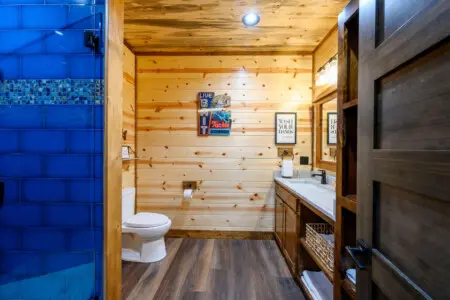 This bathroom features a fun fishing cabin vibe with knotty pine walls, modern fixtures, and a luxe walk-in shower.