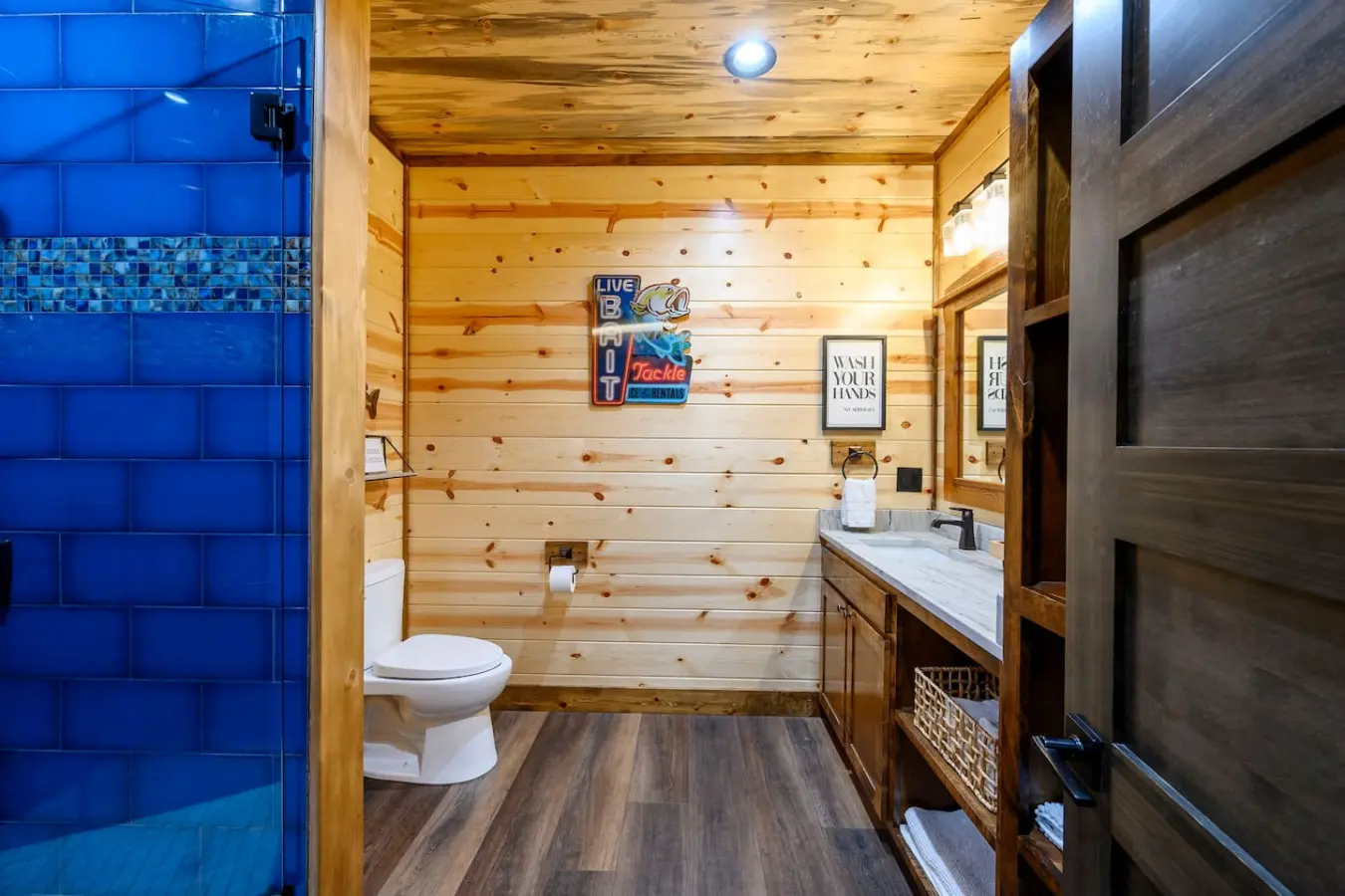 This bathroom features a fun fishing cabin vibe with knotty pine walls, modern fixtures, and a luxe walk-in shower.