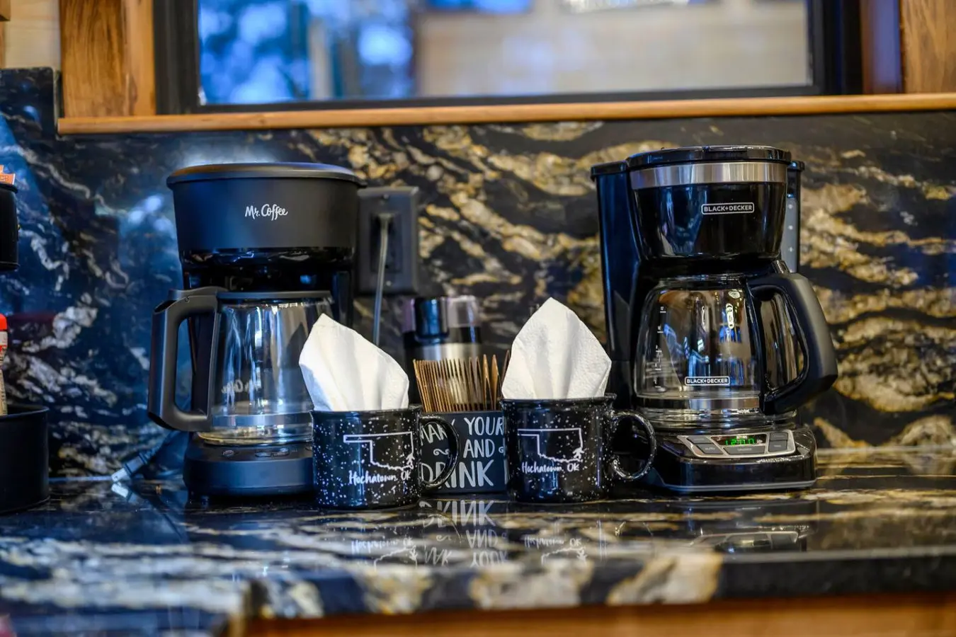 Beautiful granite countertops with a view of the lake through the window behind this well-equipped kitchen setup.