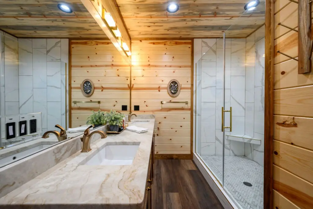 This spa-like master bath features elegant marble counters, a spacious walk-in shower, and soaring wood ceilings.