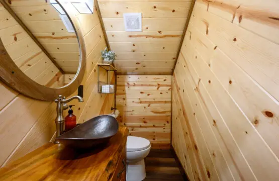This cozy wood-lined bathroom in our tiny home features a stunning handcrafted sink and all the essentials you need.