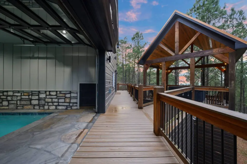 This backyard is basically a resort with a heated pool, covered pavilion, and wraparound deck overlooking the pines.