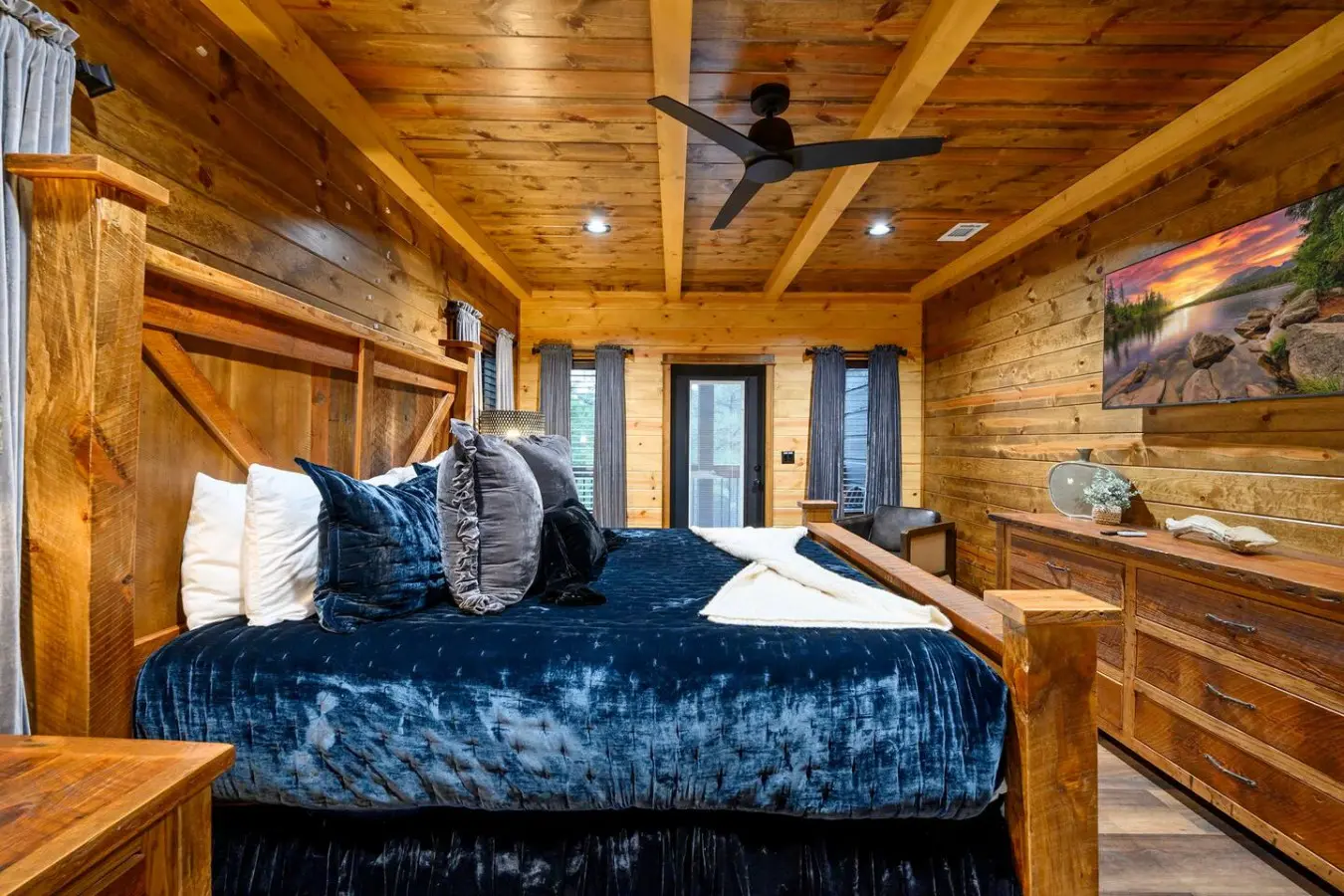 This gorgeous log cabin bedroom features a king bed, exposed beams, and those huge windows perfect for waking up to the views.