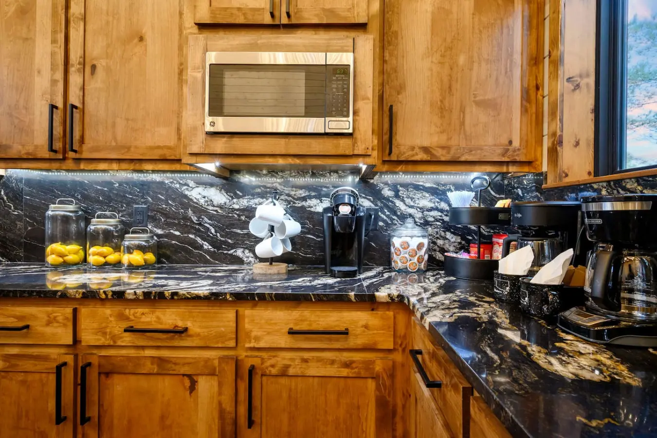 This kitchen features stunning black marble countertops and warm wood cabinetry with stainless steel appliances.