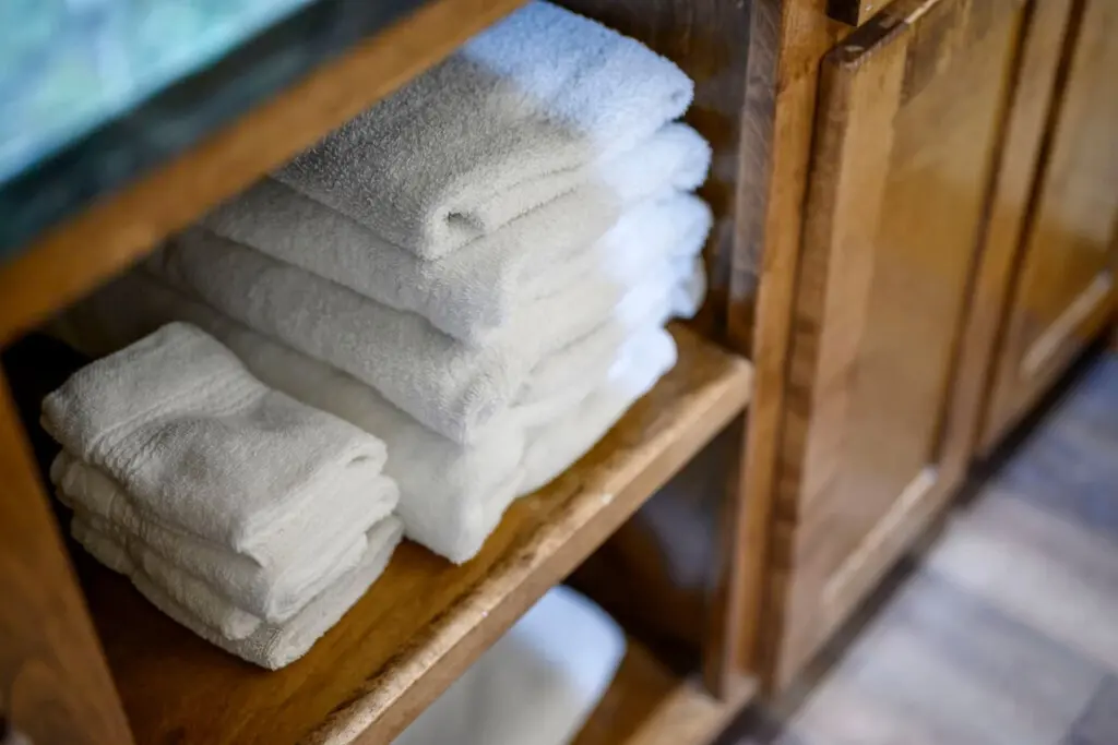 Plush rolled towels nestled in our wooden bathroom shelf, ready for you to pamper yourself.