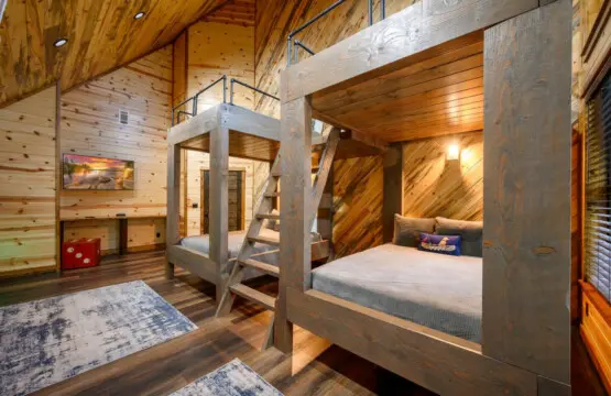 This rustic kids' bedroom features two custom log bunk beds and soaring wood-beamed ceilings perfect for family getaways.