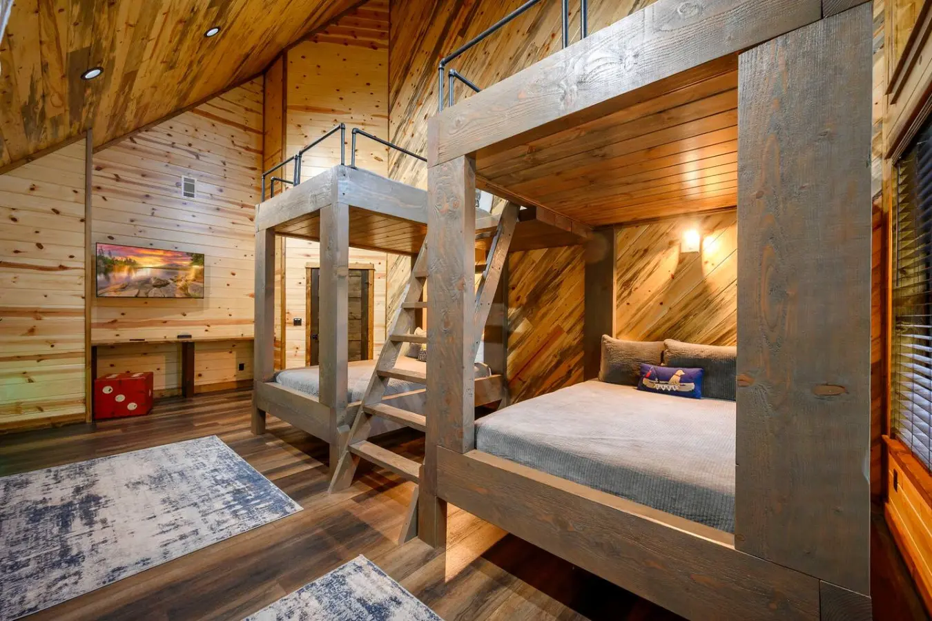 This rustic kids' bedroom features two custom log bunk beds and soaring wood-beamed ceilings perfect for family getaways.