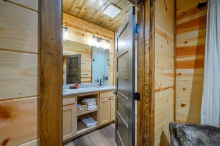 This beautiful log cabin bathroom features custom wood finishes, a spacious vanity with ample storage, and plenty of natural light.