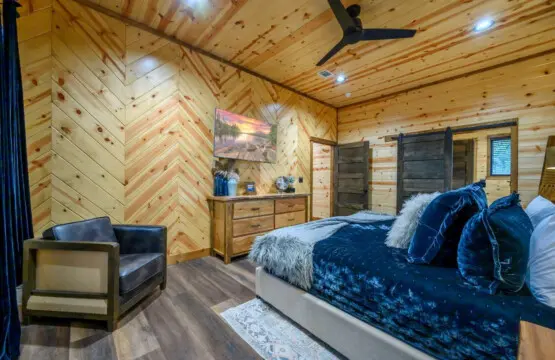 This stunning log cabin bedroom features luxe bedding, a cozy reading nook, and beautiful herringbone wood walls throughout.