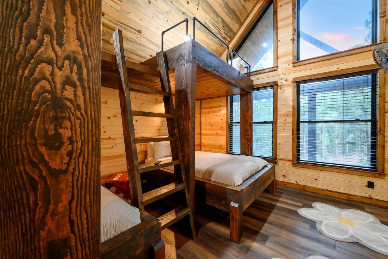 This cozy cabin bedroom features rustic bunk beds with mountain views through floor-to-ceiling windows.